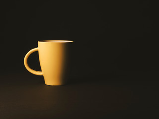 Ceramic yellow mug on a black table. Yellow mug on an isolated black background. 