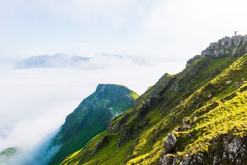 Hiker stretching arms in the air high above clouds. Faroe Islands