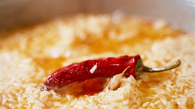 Uzbek national dish pilaf in a cauldron, red chili pepper, cooking, rice. Chili pepper close up.