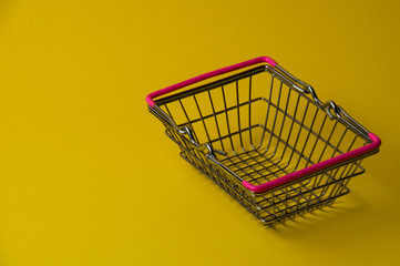 Shopping basket on a yellow background. Supermarket food price concept.