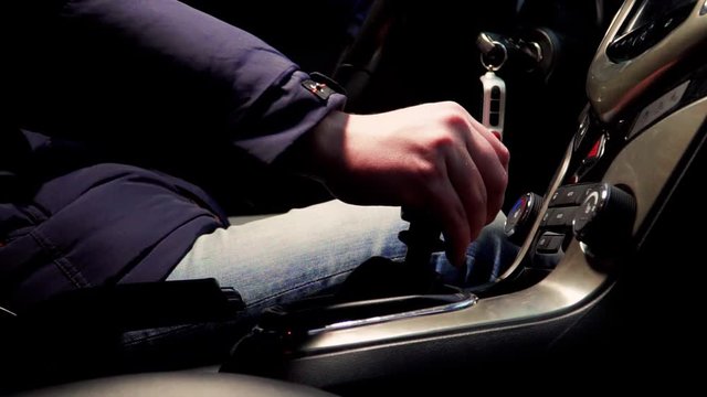a man in a car switches the manual transmission close up
