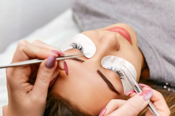Obraz na płótnie Canvas Professional beautician during eyelash extension work. Work in a beauty salon.