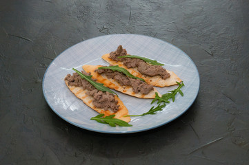 Croutons with paste and arugula. Festive snack New Year Italian dish. Top view, copy space.