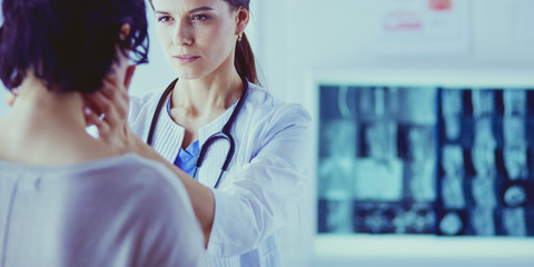 A serious female doctor examining a patient's lymph nodes