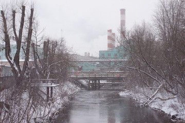 river against the background of factory pipes on a snowy day