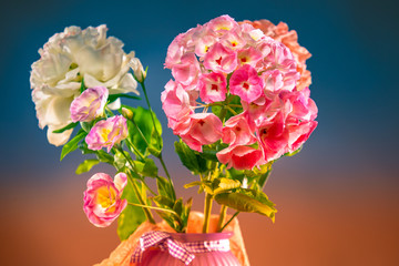 Bouquet of garden flowers on the table. Pink hydrangea, white peony and lysianthus in a vase. Flowers in a vase on a multicolored background. White and pink eustoma in a bouquet.