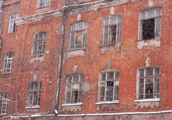Fototapeta na wymiar old red brick houses with broken Windows in heavy snow