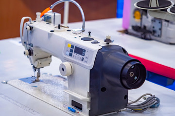 Garment industry. Industrial sewing machine in the factory. Light industry. The workplace of a seamstress. Sewing clothes. Sewing machine with overlock.