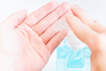 Close up of Human hand and blue alcohol gel pump bottel. Hand Sanitizer and Hygiene concept. Prevent the spread of germs and bacteria and avoid infections corona virus.