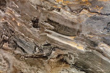 The surface, texture and background of brown marble with beige and black stripes and stains.