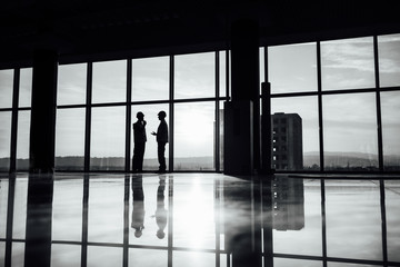 Teem of engineers looking at the panorama window, back view photo, sunset time. Black amd white photo.