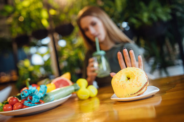 Woman choosing between apple and donut, healthy and junk food