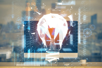 Computer on desktop in office with bulb icon hologram. Multi exposure. Concept of idea.