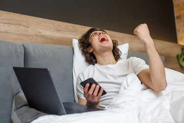 Win time, businessman working happy and relaxed from bed with laptop computer using mobile phone in workaholic concept , working from home in the morrning time