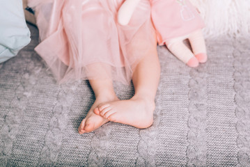 Cute little childs's bare feet lying on warm knitted blanket with soft toy. Cozy time at home, lifestyle.