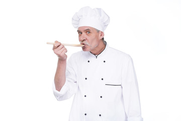 Male chef in uniform holding wooden spoon on white background