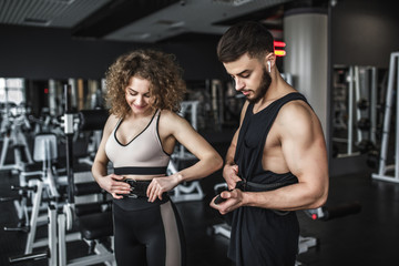 Fototapeta premium Slim woman wearing sport wears with belt, and her personal trainer during training in gym