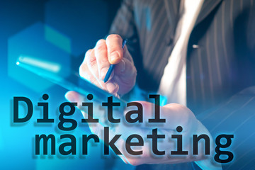 Hands with an electronic tablet and stylus on the background of the inscription Digital marketing....