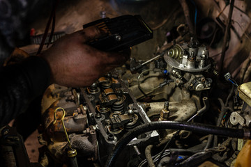 Fototapeta na wymiar A mechanic shines a flashlight on a defective engine in a car service to identify problems
