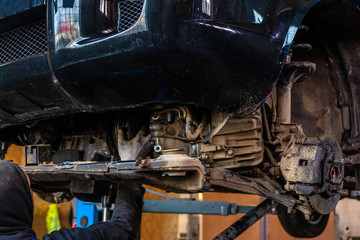 A car service worker carries out maintenance of the car after prolonged operation
