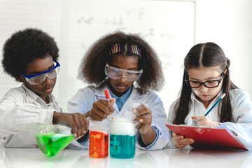 Group of teenage cute little students child learning research and doing a chemical experiment while making analyzing and mixing liquid in test tube at experiment laboratory class at school.Education