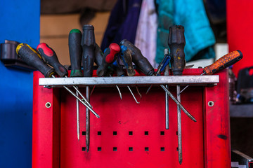 screwdrivers and wrenches in the workplace of a car repairman on a red desk with shelves