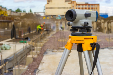 Theodolite close-up on the background of a construction site. The use of theodolite in the construction. Mapping tool. Measuring tool for determining angles. Theodolite on a tripod.