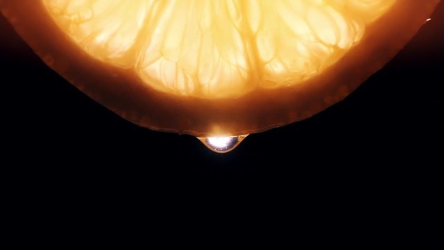 Water pouring on half slice cut of fresh lemon against black background