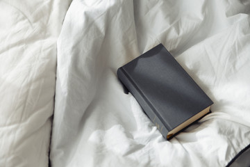 book gray on a white bedding quilt and sunbeams