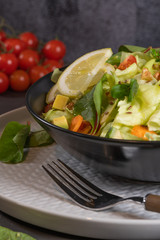 Salad. Spring vegetable salad. Fresh vegetable salad with tomatoes, apple, nuts, seeds and lemon. Olive oil pouring into bowl of salad
