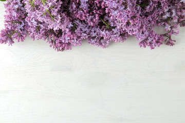 Spring flowers. Frame of twigs of blooming lilac on a white wooden table. top view. place for text
