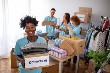 We are successful team of social workers. Woman volunteer holding a donation box and is smiling at...