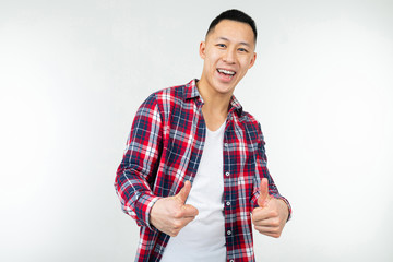 smiling asian guy in a checkered shirt wide open showing like thumb up on an isolated white studio background