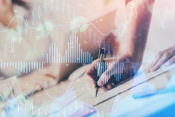 A woman hands writing information about stock market in notepad. Forex chart holograms in front. Concept of research. Double exposure