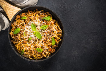 Pasta Bolognese in the skillet at black table.
