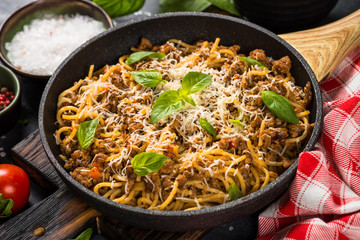 Pasta Bolognese in the skillet at black table.