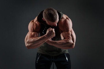 Fototapeta na wymiar Muscular white man shows biceps against a dark background.