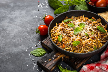 Pasta Bolognese in the skillet at black table.