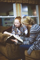 Young female friends sitting on the couch and discussing the Bible