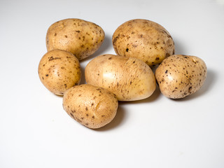 Several potatoes on a white surface. Studio photography