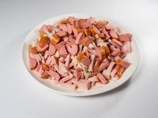 Meat and sausage slices. Preparation for soup Solyanka. A pile of chopped slices on a white round plate