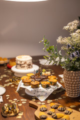 Decorated Birthday table with different cupcakes, muffins, cake and madeleines with flowers and confetti.