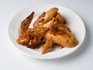 Pickled fried chicken wings on a white plate. Side view