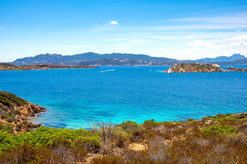Fototapeta premium Caprera Island and Spiaggia di Cala Portese harbor at the Tyrrhenian Sea coastline with Isola Porco island, La Maddalena archipelago and the Sardinian mainland in background in Sardinia, Italy