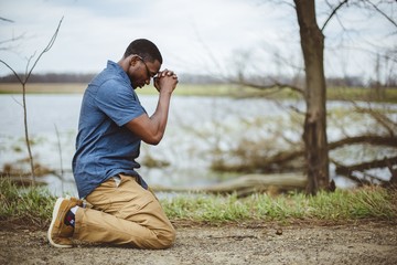Vertical shot of an African-American male praying on his knees