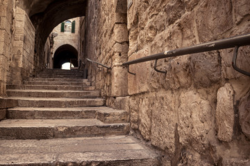 An ancient staircase, in the old Jewish Quarter alleys, arches and old-style buildings, a metal railing for disabled access. Daylight, Jerusalem, Israel.