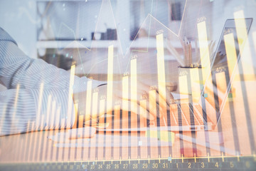 Double exposure of stock market graph with man working on laptop on background. Concept of...