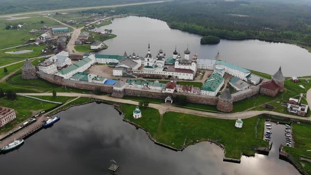 Smooth cinematic flyby of the Solovetsky monastery from the side of the White sea with a view of the Saint Lake on a cloudy day with soft lighting. 