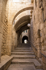 An ancient staircase, in the old Jewish Quarter alleys, arches and old-style buildings, a metal railing for disabled access. Daylight, Jerusalem, Israel.