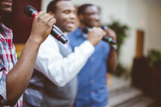 Group of African-American friends singing with microphones at the church